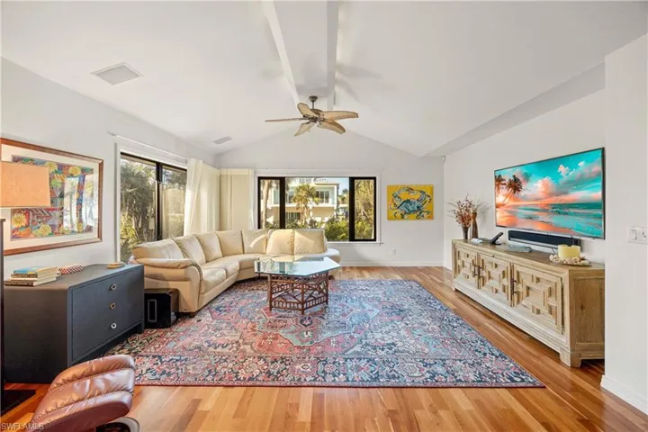 Living room with hardwood / wood-style flooring, vaulted ceiling, and ceiling fan