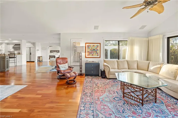 Living room with ceiling fan, light hardwood / wood-style floors, and lofted ceiling