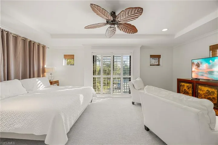 Carpeted bedroom featuring a tray ceiling, access to exterior, ceiling fan, and crown molding