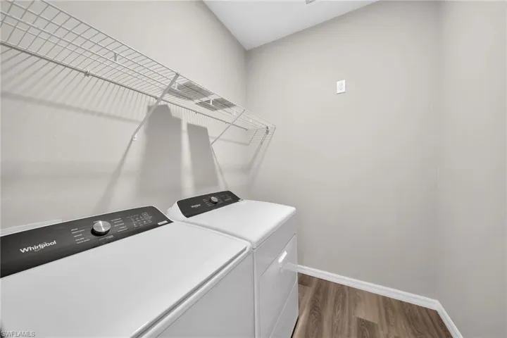 Clothes washing area with dark wood-type flooring and washing machine and clothes dryer