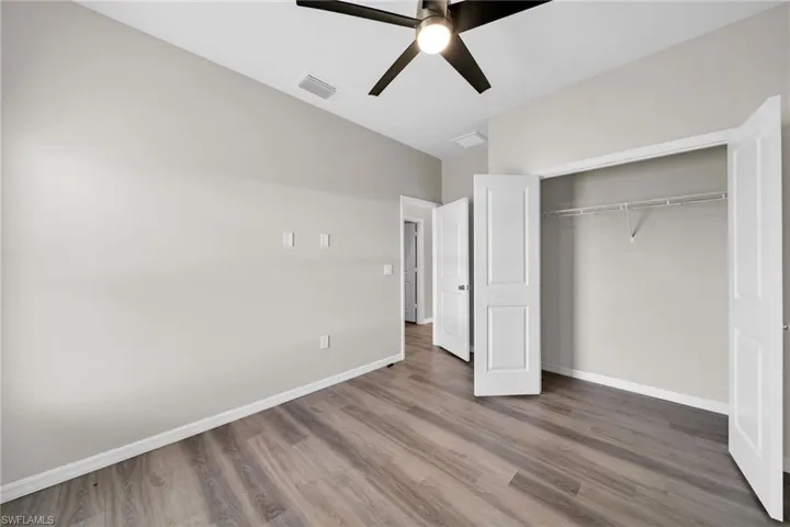 Unfurnished bedroom with wood-type flooring, lofted ceiling, ceiling fan, and a closet