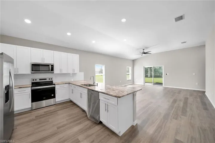 Kitchen with appliances with stainless steel finishes, sink, kitchen peninsula, and a wealth of natural light