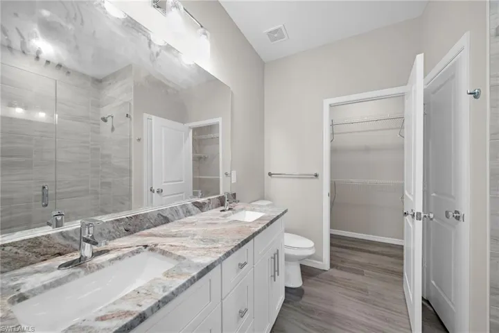 Bathroom with vanity, hardwood / wood-style flooring, toilet, and a shower with door