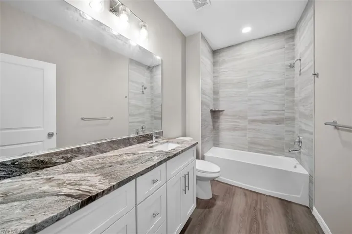 Full bathroom featuring tiled shower / bath combo, vanity, toilet, and hardwood / wood-style flooring