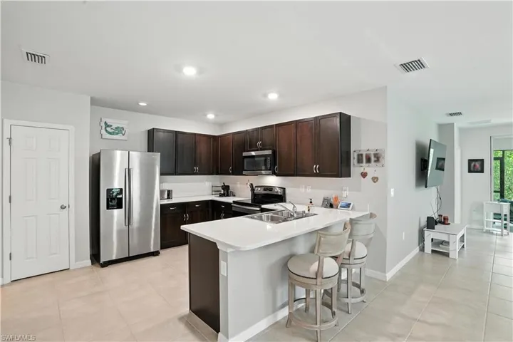 Kitchen with appliances with stainless steel finishes, raised cabinetry, quartz countertops