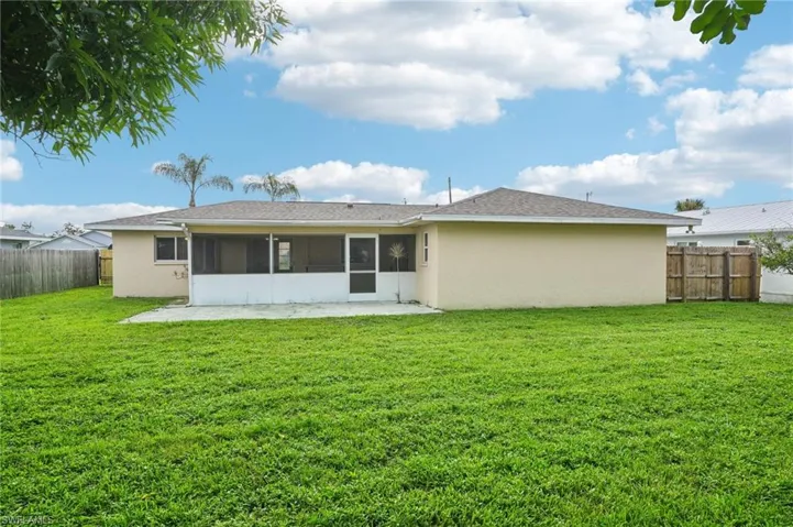 Back of house with a sunroom and a lawn