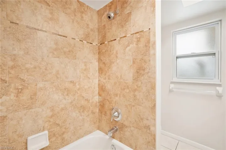 Bathroom with tiled shower / bath and tile patterned floors