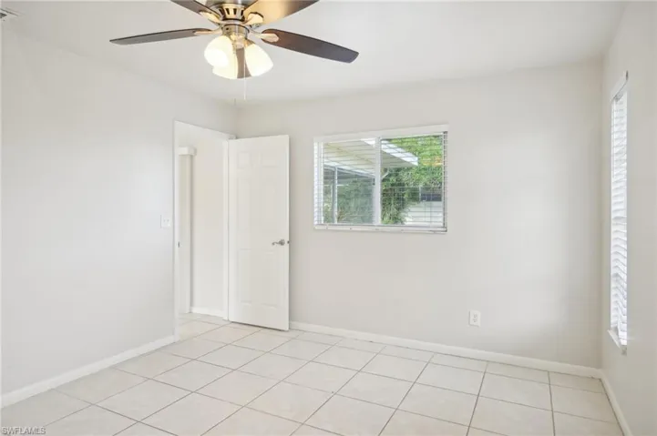 Empty room with light tile patterned floors and ceiling fan