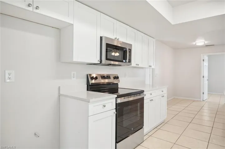 Kitchen with white cabinets, light tile patterned flooring, and appliances with stainless steel finishes