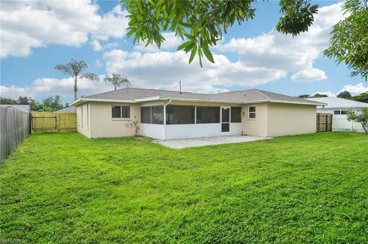 Rear view of house with a sunroom and a lawn