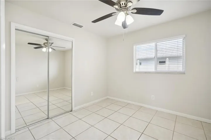 Empty room featuring light tile patterned flooring and ceiling fan