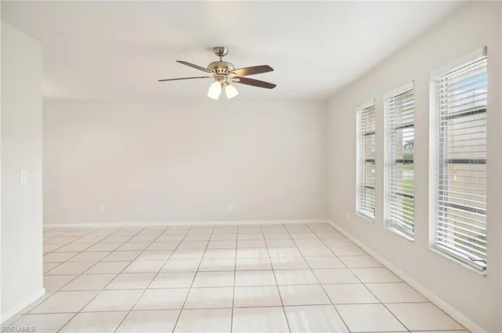 Tiled empty room with ceiling fan and a wealth of natural light