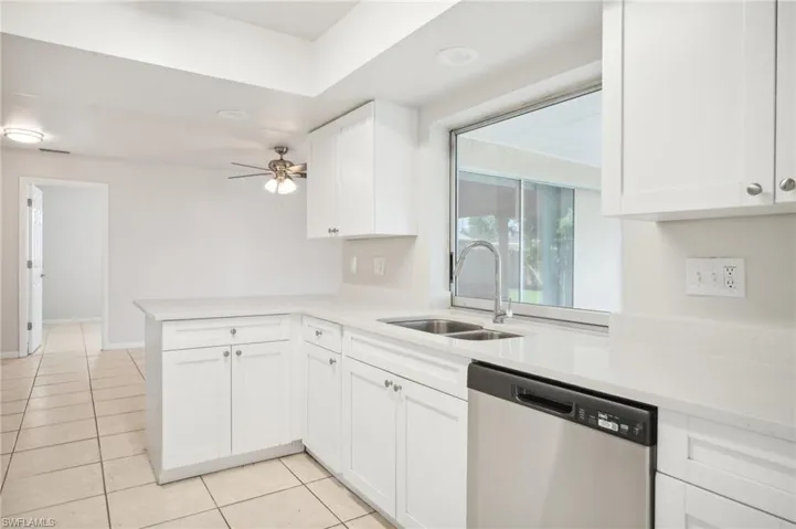 Kitchen featuring sink, kitchen peninsula, white cabinetry, dishwasher, and ceiling fan