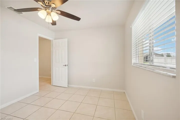 Empty room with light tile patterned floors and ceiling fan
