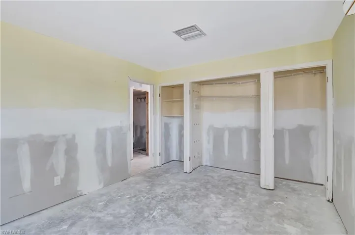 Unfurnished bedroom featuring multiple closets and concrete flooring