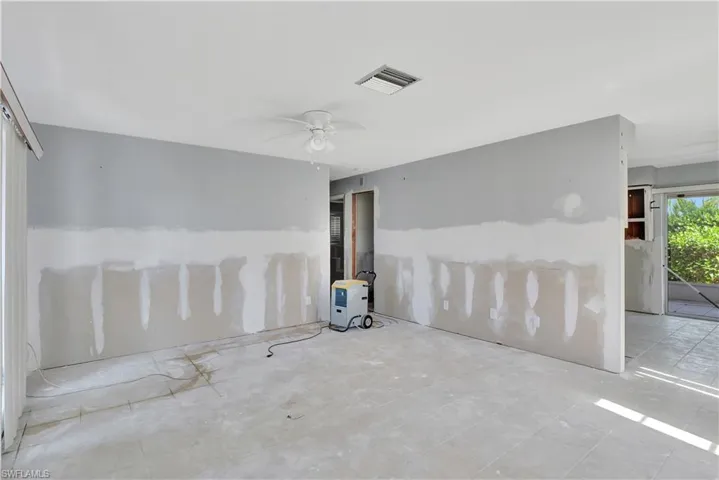 Empty room with ceiling fan and light tile floors