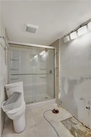 Bathroom featuring tile flooring, an enclosed shower, and toilet