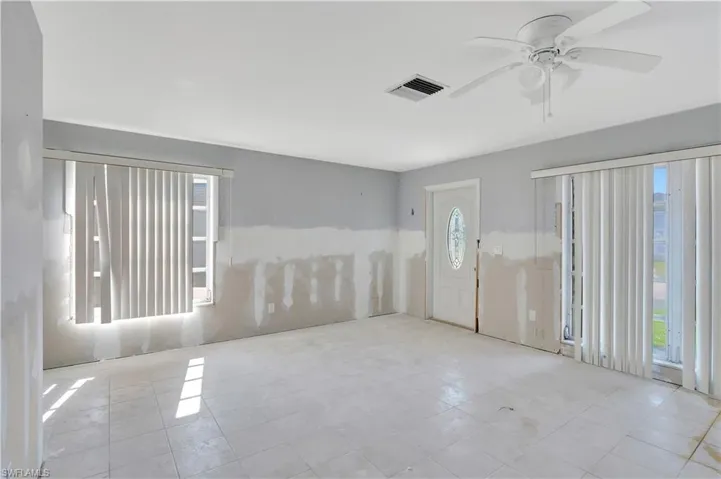 Tiled spare room featuring ceiling fan