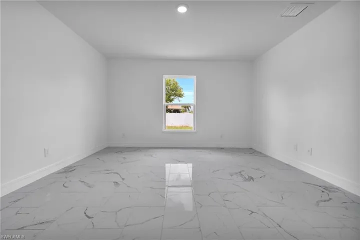 Spacious interior room featuring large format marble-look tile flooring and crisp white walls