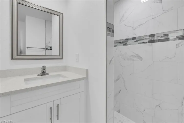 Bathroom featuring a white vanity with a light-colored countertop, an undermount sink, and a framed mirror
