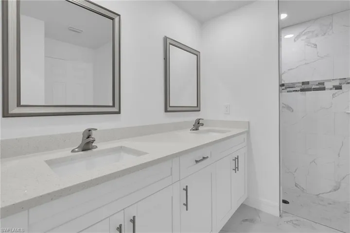 Dual vanity featuring white shaker-style cabinetry, light-toned countertops, and undermount sinks