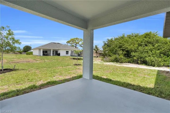Covered concrete patio overlooking a expansive grass yard