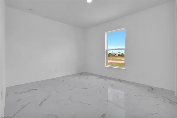 Bright interior space featuring a window, white walls, and large format tile flooring