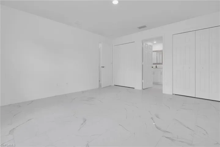 Spacious room featuring light-colored walls and large-format porcelain tile flooring