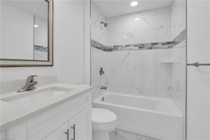 Bathroom featuring a white vanity with a quartz-finish countertop, undermount sink, and brushed nickel faucet