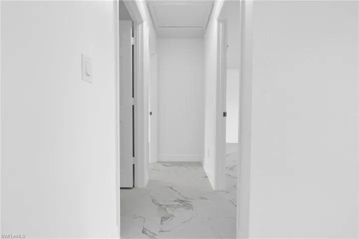 Hallway featuring white walls, white trim, and light-toned, patterned flooring