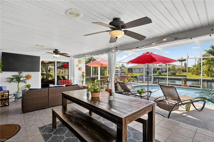 View of patio with outdoor dining area, an outdoor hangout area, an outdoor pool, a water view, and a ceiling fan