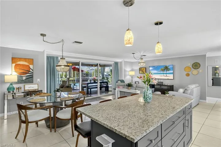 Kitchen with light stone countertops, light tile patterned floors, crown molding, and open floor plan