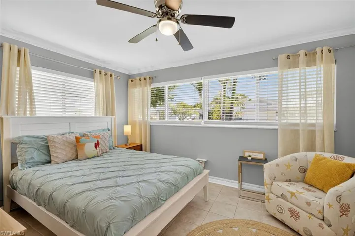 Tiled bedroom featuring crown molding and a ceiling fan