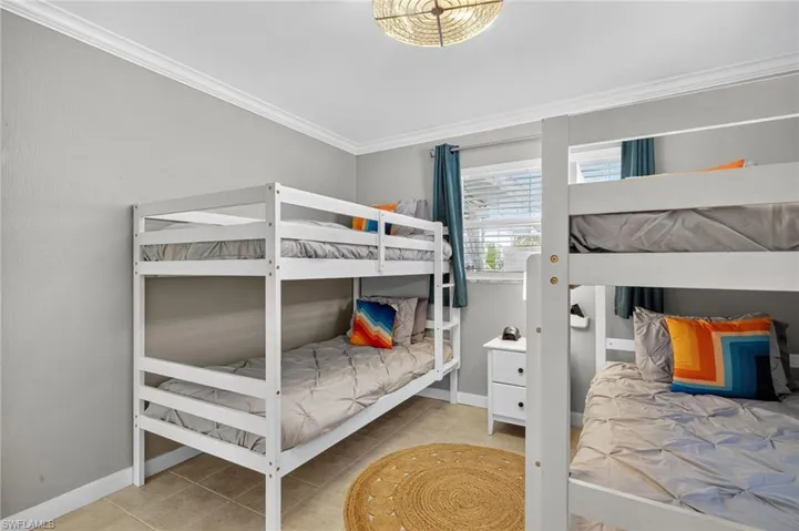 Bedroom with crown molding and light tile patterned floors