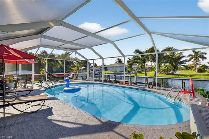 Outdoor pool with a boat dock, a water view, boat lift