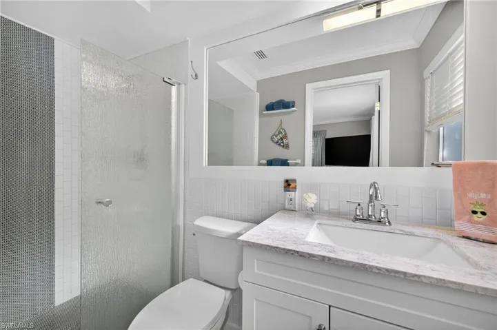 Full bath with a stall shower, vanity, crown molding, tile walls, and tasteful backsplash