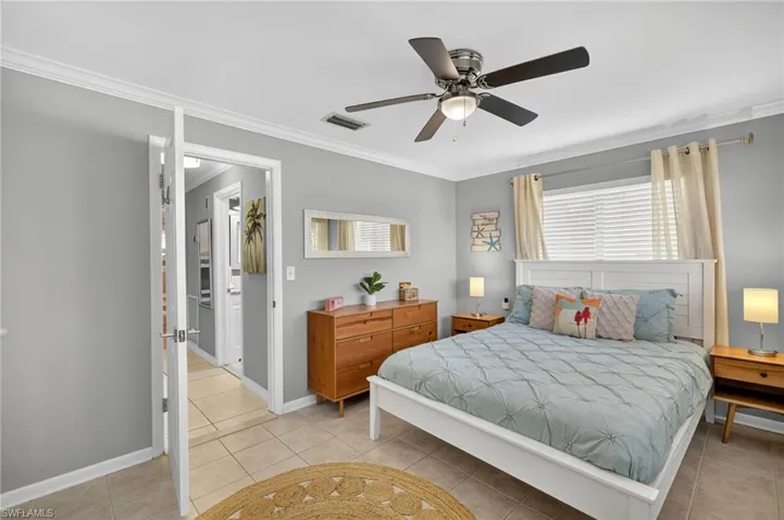Bedroom with crown molding, light tile patterned floors, and ceiling fan