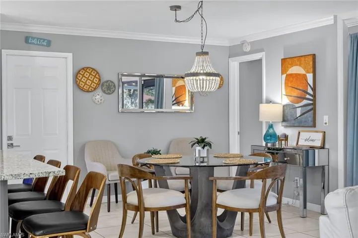 Bedroom with multiple windows, ornamental molding, light tile patterned flooring, and freestanding refrigerator