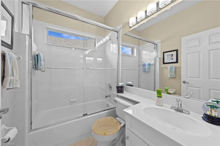 Full bath featuring combined bath / shower with glass door, vanity, and tile patterned flooring