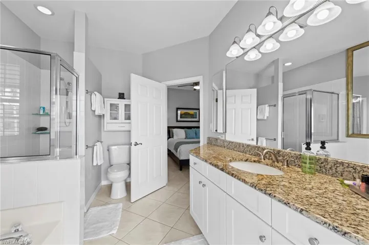 Ensuite bathroom with vanity, light tile patterned flooring, a stall shower, ceiling fan, and a garden tub