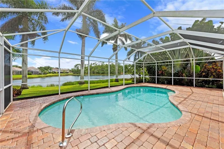 Outdoor pool featuring a sunroom, a patio, a water view, a lanai, and a yard