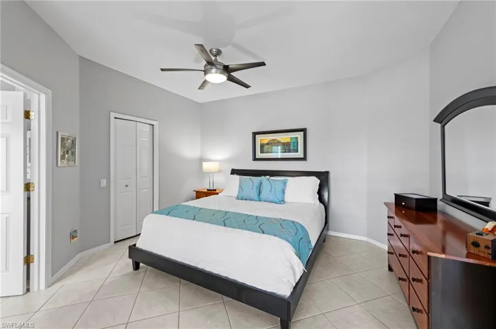 Bedroom featuring light tile patterned floors, a ceiling fan, and a closet