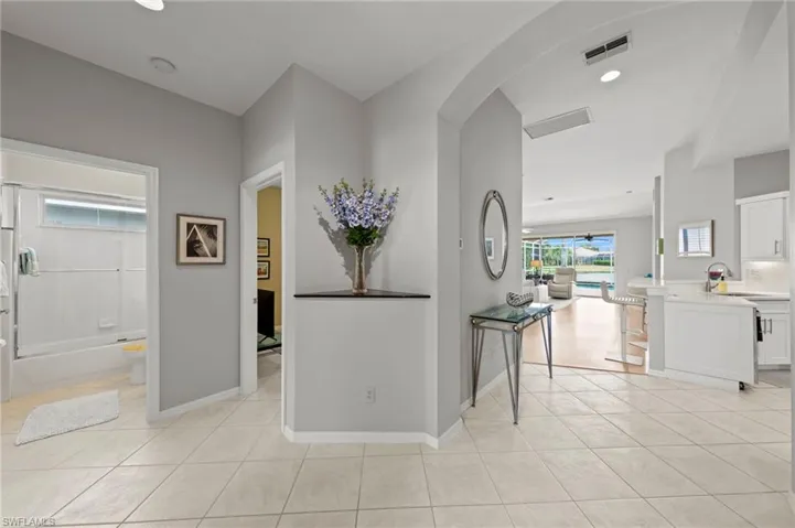 Hallway featuring arched walkways, light tile patterned floors, and recessed lighting