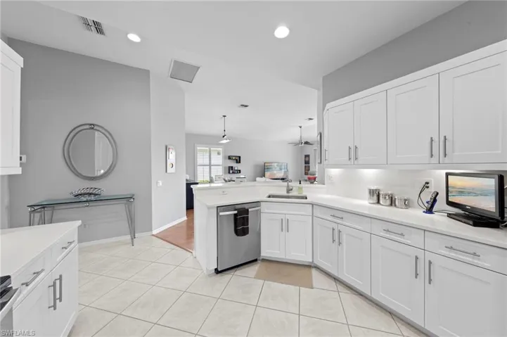 Kitchen with white cabinets, stainless steel appliances, a peninsula, recessed lighting, and light tile patterned flooring