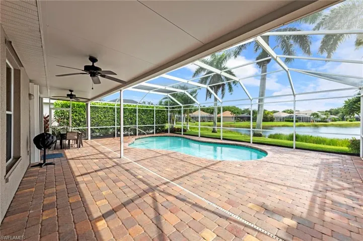 Swimming pool featuring a sunroom, a patio area, a lanai, a water view, and a grill