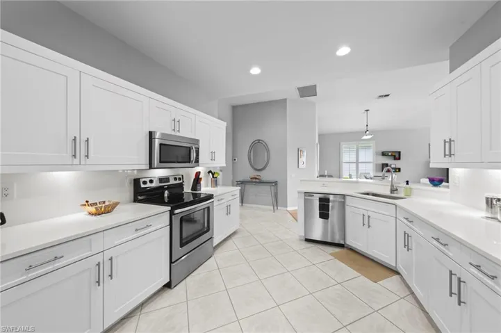 Kitchen with appliances with stainless steel finishes, white cabinetry, pendant lighting, recessed lighting, and light tile patterned floors