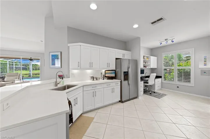 Kitchen with stainless steel fridge with ice dispenser, a peninsula, light tile patterned floors, white cabinetry, and recessed lighting