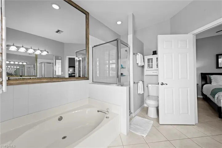 Ensuite bathroom with a shower stall, light tile patterned floors, a bath, and recessed lighting