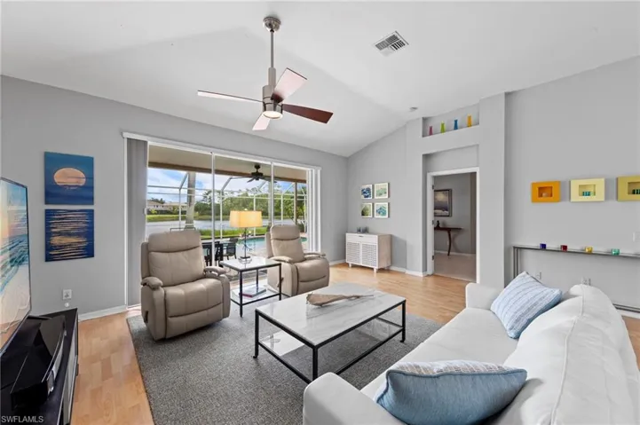 Living room featuring lofted ceiling, light wood finished floors, and a ceiling fan
