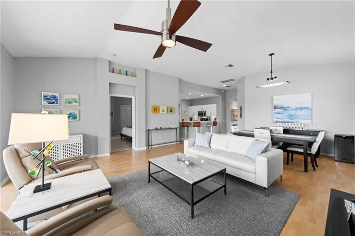 Living room featuring vaulted ceiling, light wood finished floors, and a ceiling fan